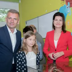 Bartosz Arłukowicz z córką i koleżanką na tle kolorowej ściany z bajkowymi zwierzątkami.