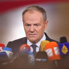 Donald Tusk w Ustroniu, otoczony przez mikrofony mediów, gotów do udzielenia wywiadu.