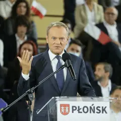 Donald Tusk przemawia na konwencji po w Płońsku. W tle widzowie z polskimi flagami.