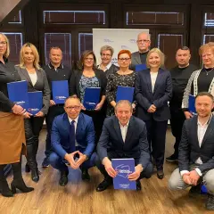 Grupa osób pozuje do zdjęcia z niebieskimi folderami. Na folderach widnieje napis "Platforma Obywatelska".
