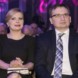 Patrycja Kotecka, żona Zbigniewa Ziobro, w czarnej sukience, siedzi obok męża w garniturze.