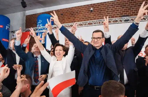 Radosny tłum z polskimi flagami i znakami zwycięstwa. W centrum Mateusz Morawiecki i inni politycy PiS, być może świętujący sukces, mimo że lista afer PiS jest długa.
