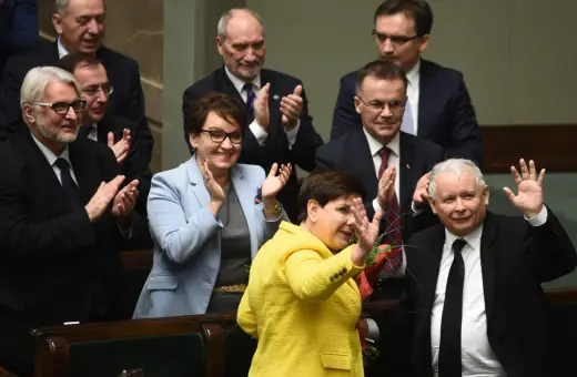 Kiedy rządził PiS, Beata Szydło w żółtej marynarce i Jarosław Kaczyński w garniturze pozdrawiają tłum.