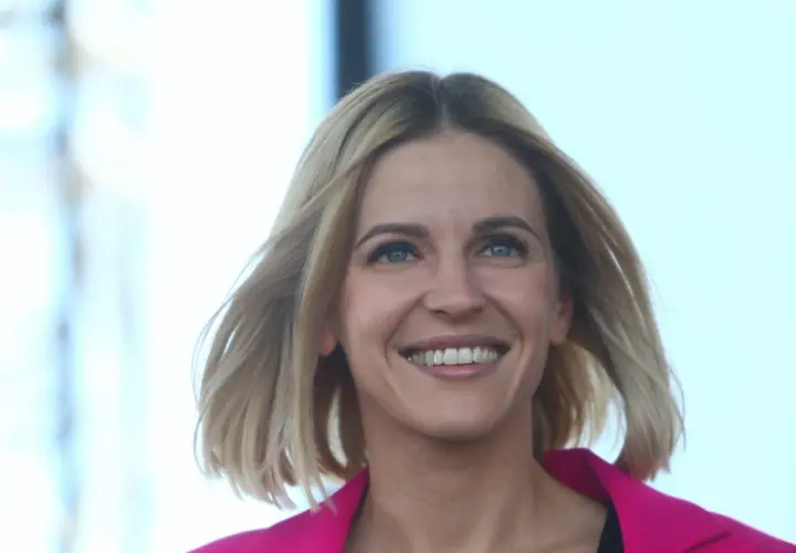 Uśmiechnięta Aleksandra Gajewska, której wykształcenie jest szeroko komentowane, w różowym żakiecie.