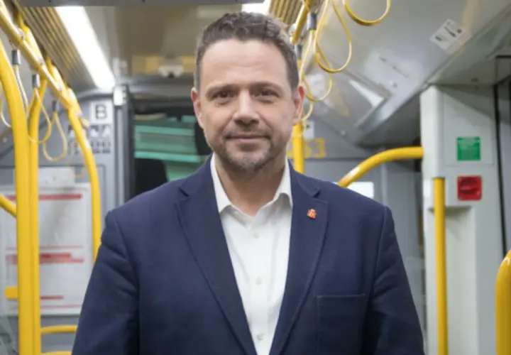 Rafał Trzaskowski, prezydent Warszawy, w środkach komunikacji miejskiej. Jego życiorys to historia zaangażowania w rozwój stolicy.