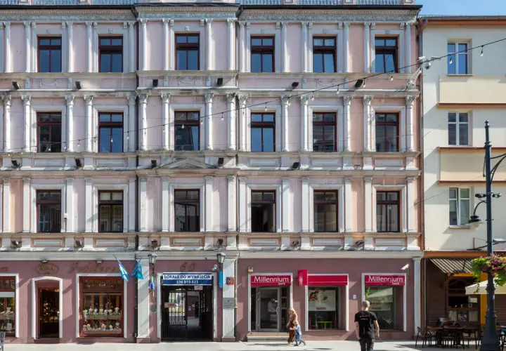 Kamienica przy ul. Piotrkowskiej 61 w Łodzi. Elegancka fasada z licznymi oknami i zdobieniami. Na parterze sklepy, m.in. jubiler i bank.