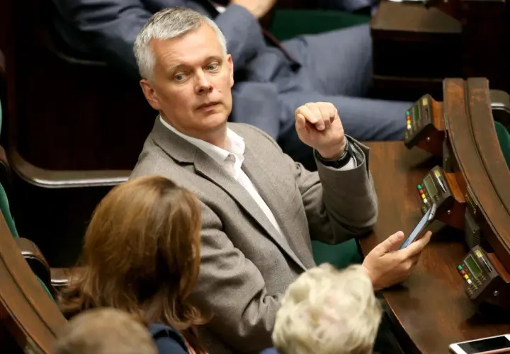 Tomasz Siemoniak, polityk o polskim pochodzeniu, w parlamencie, z telefonem w dłoni.