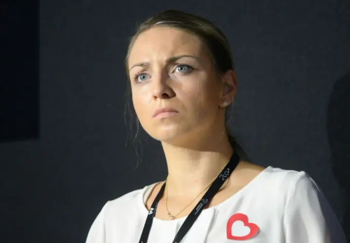 Posłanka Kinga Gajewska z zamyśloną miną, w białej bluzce z czerwonym sercem.