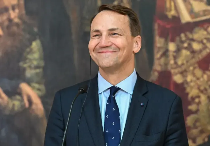 Uśmiechnięty Sikorski, który polityk? W tle obraz z postaciami.