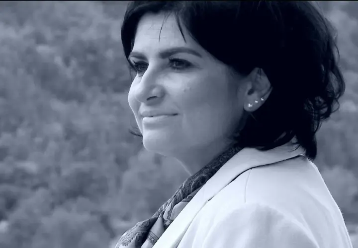Portret Agnieszki Kołacz Leszczyńskiej w białej marynarce, z delikatnym uśmiechem i ozdobnymi kolczykami.