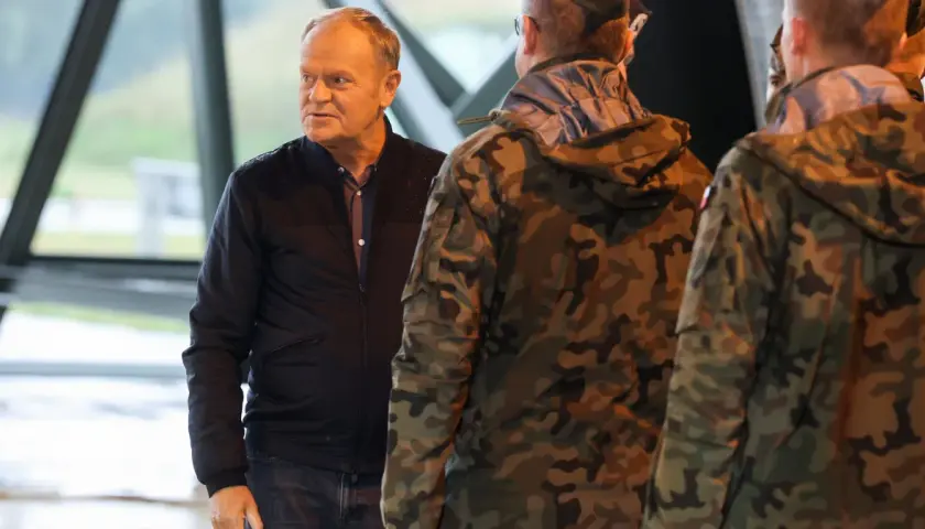 Donald Tusk rozmawia z żołnierzami w mundurach. Czy Donald Tusk był w wojsku? Nie ma informacji, by służył w armii.