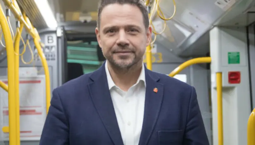 Rafał Trzaskowski, prezydent Warszawy, w środkach komunikacji miejskiej. Jego życiorys to historia zaangażowania w rozwój stolicy.