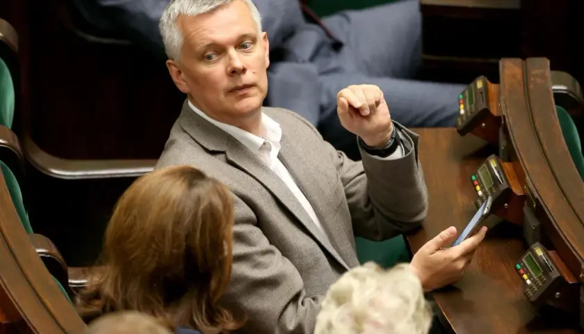 Tomasz Siemoniak, polityk o polskim pochodzeniu, w parlamencie, z telefonem w dłoni.
