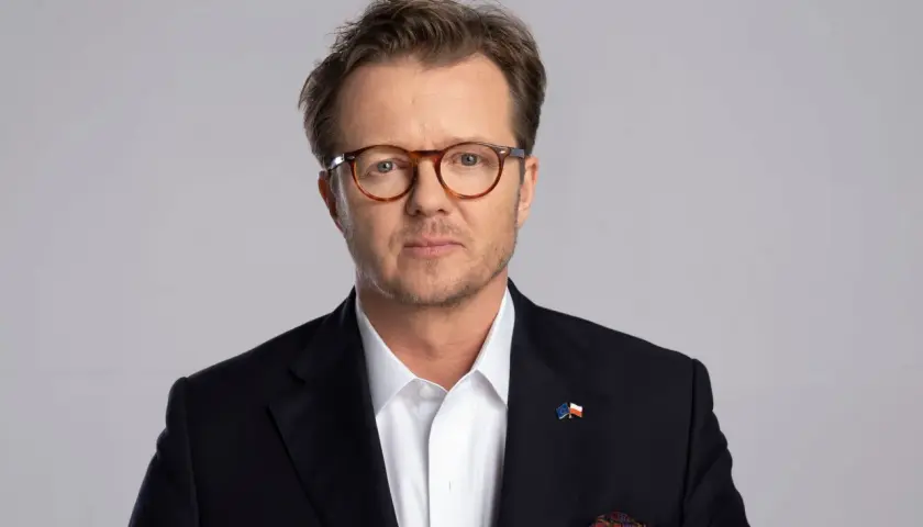 Michał Wawrykiewicz, prawnik i działacz społeczny, w garniturze z flagami UE i Polski. Jego życiorys to historia walki o prawa obywatelskie.