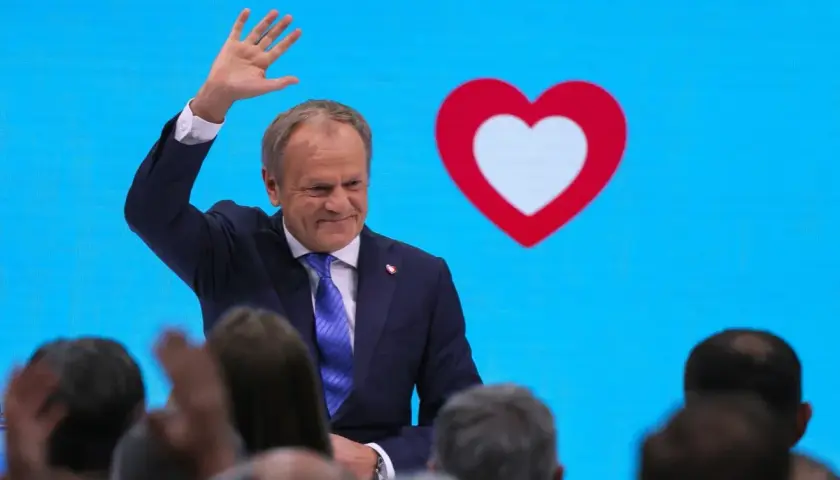 Donald Tusk macha do tłumu na tle niebieskiego ekranu z sercem. Czy to koalicja?