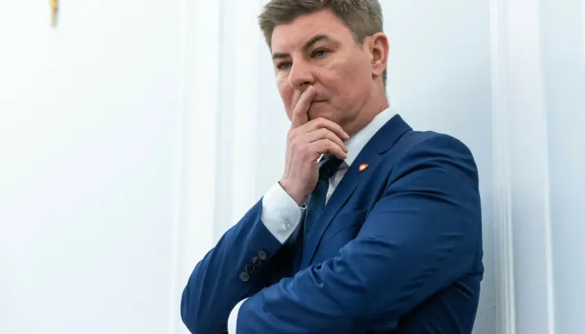 Jan Grabiec w garniturze, zamyślony, z palcem przy ustach. Może myśli o przyszłości dzieci?