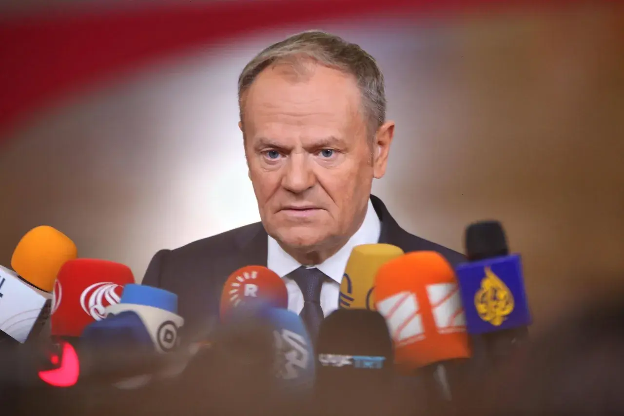 Donald Tusk w Ustroniu, otoczony przez mikrofony mediów, gotów do udzielenia wywiadu.
