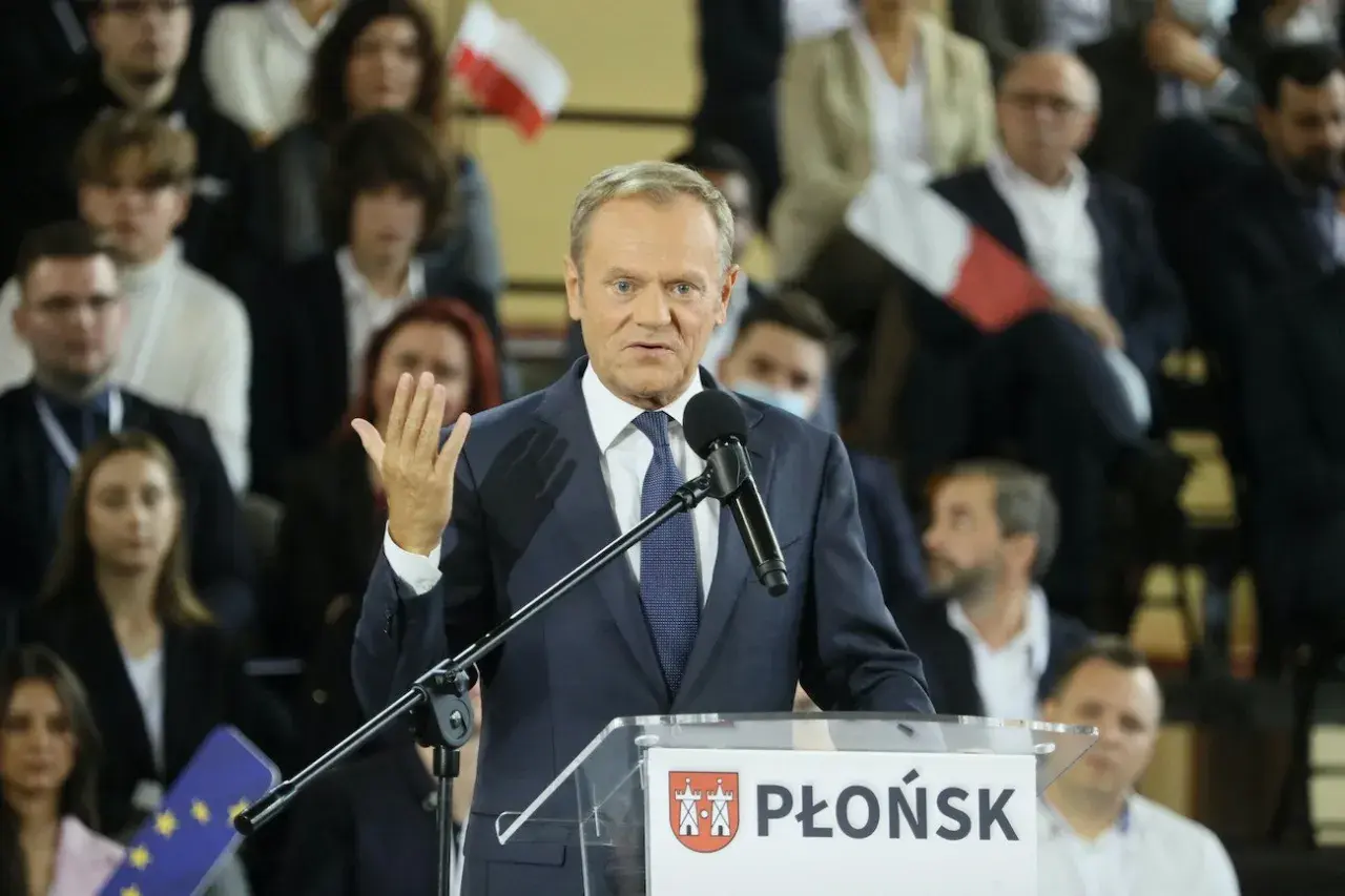 Donald Tusk przemawia na konwencji po w Płońsku. W tle widzowie z polskimi flagami.