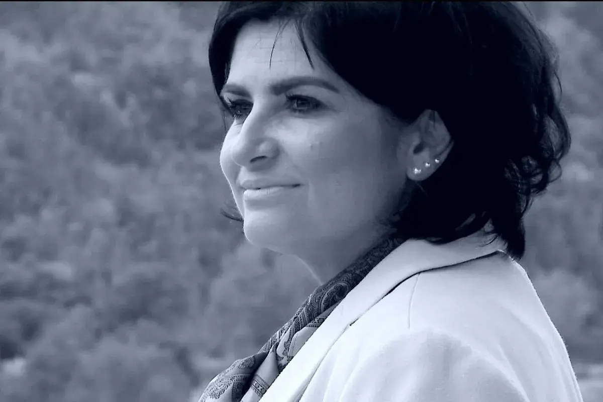 Portret Agnieszki Kołacz Leszczyńskiej w białej marynarce, z delikatnym uśmiechem i ozdobnymi kolczykami.