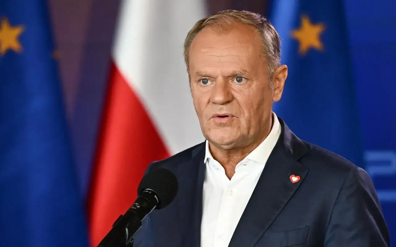 Donald Tusk przemawia na konwencji po płońsku, w tle flagi Polski i UE.