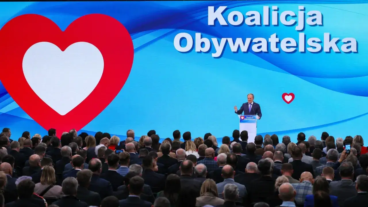 Mężczyzna przemawia na tle wielkiego serca i napisu