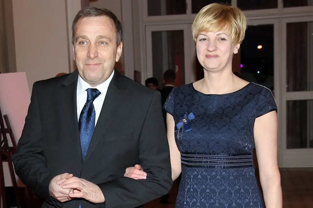 Cezary Grabarczyk z żoną, w eleganckich strojach, idą ramię w ramię. Może właśnie wracają po odebraniu nagrody, a ich dzieci czekają na nich z niecierpliwością.
